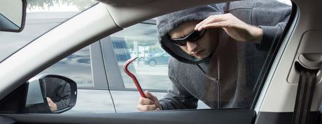 Top 5 Things You Should Never Leave in Your Car - image of a burglar attempting to break into a vehicle.